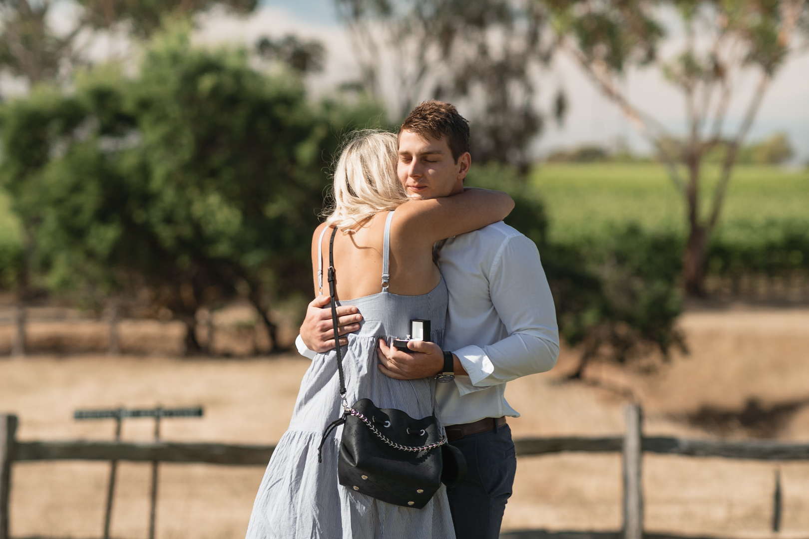 Young couple hugging after agreeing to proposal at a picnic in a winery