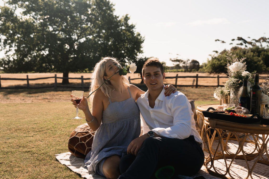 Carefree couple indulged in wine and cheese after proposal and mini engagement shoot with proposal photographer